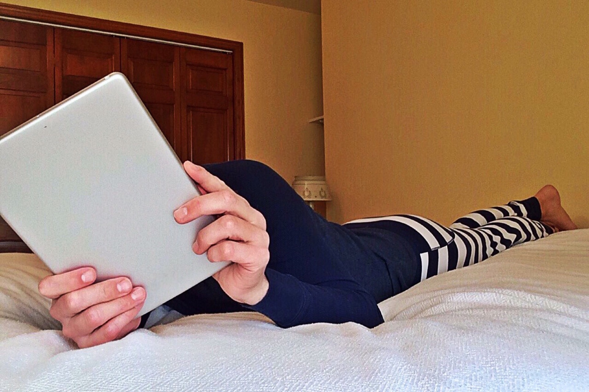 Person lying on bed using a tablet